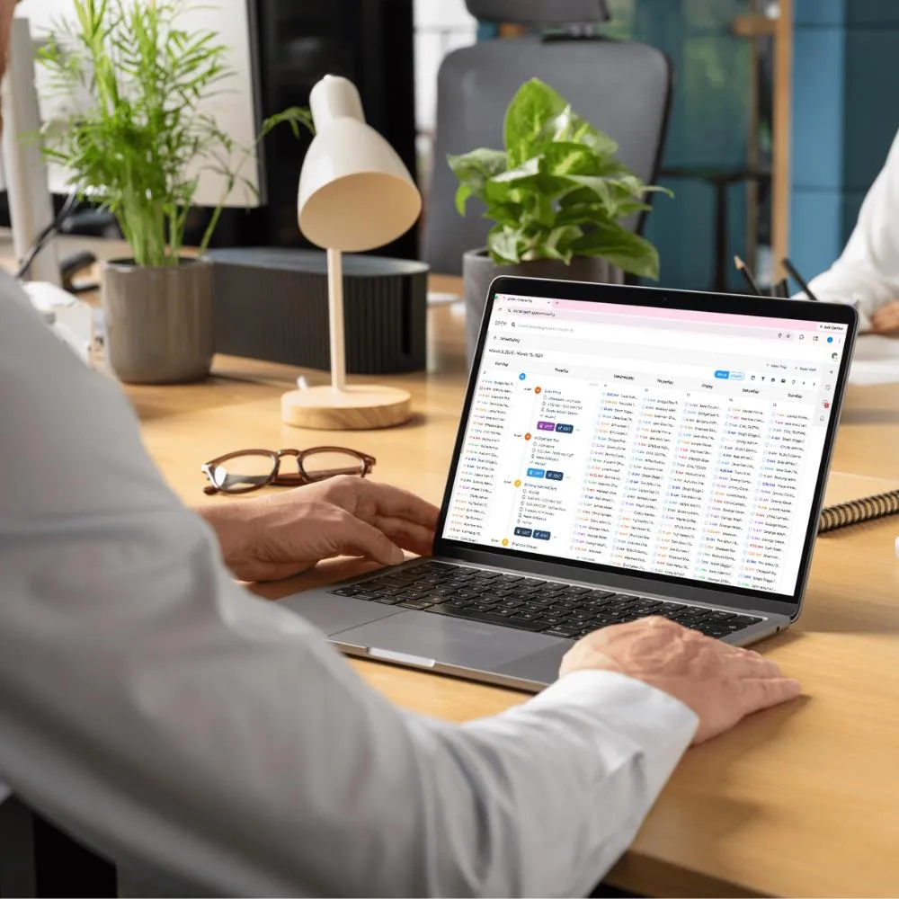 An agency owner reviewing the SMART Scheduling calendar view in GEOH on a laptop.